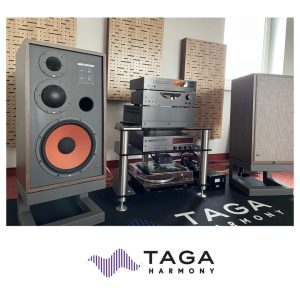 Credits: Mark Gusew | StereoNET TAGA Harmony is a Polish audio manufacturer that started in the early nineteen nineties. Besides creating a large range of loudspeakers, it also has a sizeable catalogue of electronics and accessories. The name comes from the first letters of the company's tagline, which is 'To Achieve Glorious Acoustics', no less. It is gradually building its presence in Europe as an affordable audio brand, winning awards and expanding internationally. The products are designed in the European Union and manufactured in China. This company sells bookshelves, floorstanding, surround sound, subwoofer speakers, and a custom install range that includes in-wall, in-ceiling, and outdoor. The striking, retro-styled Nostalgic TH-12 reviewed here features a 305mm woofer in a three-way configuration. It's a chunky bass-reflex design with the port in the front panel. The 25mm tweeter and 50mm midrange driver are hidden behind black domed metal covers. Also on the front panel are pads to control the levels of the tweeter and midrange drivers relative to the bass driver. There are three settings, -3dB, 0dB, and +3dB, centred on 800Hz and 3kHz. All drivers are designed in-house and appear to be of high quality. The tweeter is made from an exotic titanium and magnesium alloy with a polyester surround and a 25mm aluminium voice coil with CCA wires for accuracy. It has an oversized magnet design. The midrange driver uses an aluminium dome, also with a stiff yet flexible polyester surround with an oversized magnet. The bass driver sports a paper/polyester cone with a U-type rubber surround, a Terylene dust cap and an aluminium injection-moulded frame. The crossover has been designed to use as few components as possible. High-quality polyester capacitors and premium inductors are utilised, along with silver-clad 4N (99.99%) single-crystal copper wiring. Stated crossover points are at 800Hz and 2.5kHz. The published frequency response of the speaker is 30Hz to 20kHz (±3dB). It has a claimed nominal impedance of 6 ohms, and sensitivity is 92dB, so this speaker should be a reasonably easy load for most modern solid-state amplifiers. Maximum input power is 250W. The cabinet measures 740x420x340mm [HxWxD], making it wider than most modern designs. Each speaker weighs 29.6kg and is made from 18mm thick MDF. The supplied removable grilles are unusually solid and feature a high-quality vintage-style cloth. Around the back is a single pair of multiway speaker binding posts of decent quality. The available cabinet finishes are natural walnut and oak. Each pair of Nostalgic TH-12 speakers comes with a standard pair of dedicated speaker stands, which are the correct height and size to isolate the speakers from the floor and provide firm support. The stand is tilted backwards at 5 degrees to time-align the drive units, and is made of thick, 6x6cm steel frame that's painted matt grey. Mounting bolts are provided to solidly affix the speaker to the stand, which is very heavy at around 12.5kg. I found these speakers worked best on their dedicated stands, positioned with the mirror-image tweeters facing inwards towards one another. The user manual suggests that the speakers will sound even better after proper running in, and I concur with this. I positioned my review pair well away from the front and side walls, to achieve the best balance of bass weight and clarity, and toed in slightly. I used a Yamaha R-N2000A amplifier rated at 120W RMS per channel into 8 ohms for my listening tests. THE LISTENING This loudspeaker has an attractively balanced sound, yet is still capable of generating real excitement. It has a big character to match its physicality, and can sound great at low listening levels – and then go loud with very little sign of stress. I enjoy listening to Chad Crouch's compositions playing softly as background music while I'm researching and writing. I sit well off-axis, to the side of the room where my desk is located, and even there, I can enjoy the realism of the naturally recorded birds and instruments on the track Part 17. Even when the track has no bass content, the Nostalgic TH-12 still sounds smooth and uniform in the treble and midrange, and shows a seamless transition between its drivers. There is a fine sense of fluidity, evenness, and composure to voices and piano, in particular, which is very enjoyable and leaves me wanting to listen longer. With the ability to tweak treble and midrange levels, the TH-12 is capable of delivering a reasonably even frequency response – certainly one that should be to most people's tastes. Listening to The Rhythm Divine by Yello and featuring the amazing voice of Shirley Bassey, I can hear a satisfying sense of detail, speed and air. The music sounds atmospheric, with well placed backing vocals and sparkling cymbal work. It's a warm and friendly sound, with no harshness or irritation whatsoever. Rachets by Hedegaard is a track with strong rhythmic bass, and this TAGA Harmony speaker delivers room-filling energy, plus a thump in the chest from the kick drum. All the same, it doesn't go quite as low as other designs I've tried in my listening room – the recently reviewed PSB Imagine T65 speaker felt quite a bit deeper, for example, despite being physically smaller. All the same, the tuneful bass is fun to listen to. You certainly would not call this an old-school party boom box, but it's a pleasure to hear all the same. Such refinements are put to good use on New York City by The Peter Malick Group, featuring Norah Jones. Tonally, the mix is virtually perfect, which is quite an achievement for an inexpensive loudspeaker. I especially like the impeccable timing of the guitar and percussion work. One particular highlight is the doubling-up of Norah's voice in the chorus, with the keyboard in the background. If you listen intently for small details in your favourite tracks, the TH-12 will ingratiate itself to you. The soundstaging is very good indeed. I loved how the speaker practically disappears from the room at higher volumes, letting the listener focus in on the music playing. In this respect it is more convincing than many other speakers I've heard, even at multiples of the TAGA Harmony's asking price. For instance, the blues-influenced Evil Memory by Crystal Shawanda has a broad spread of sound that pushes well beyond the speaker boxes, with the vocal line clearly set forward of the instruments. This speaker recreates the recorded acoustic convincingly, helping to fully impart the realism of the performance. TAGA Harmony Nostalgic TH-12 Floorstanding Loudpeakers Review